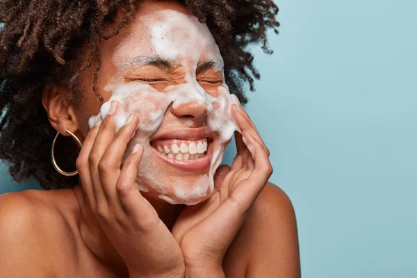 Kobieta oczyszcza twarz przy pomocy mocno pieniącego się produkt